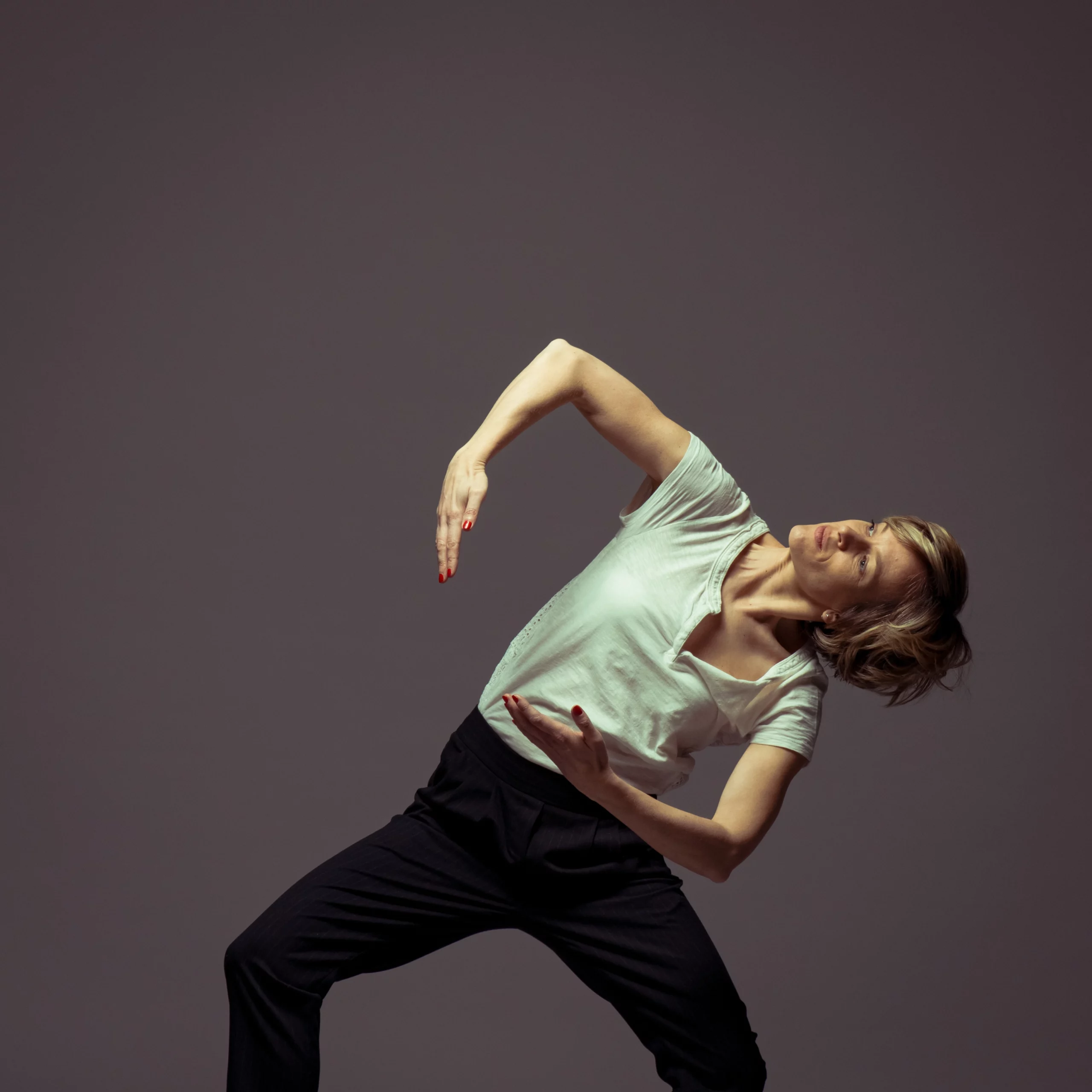 Gros plan sur Marina, experte en mouvement, dans une posture de danse expressive et précise. Son regard et l'alignement de ses bras illustrent la conscience corporelle et la fluidité enseignées dans la méthode Mov'Art®