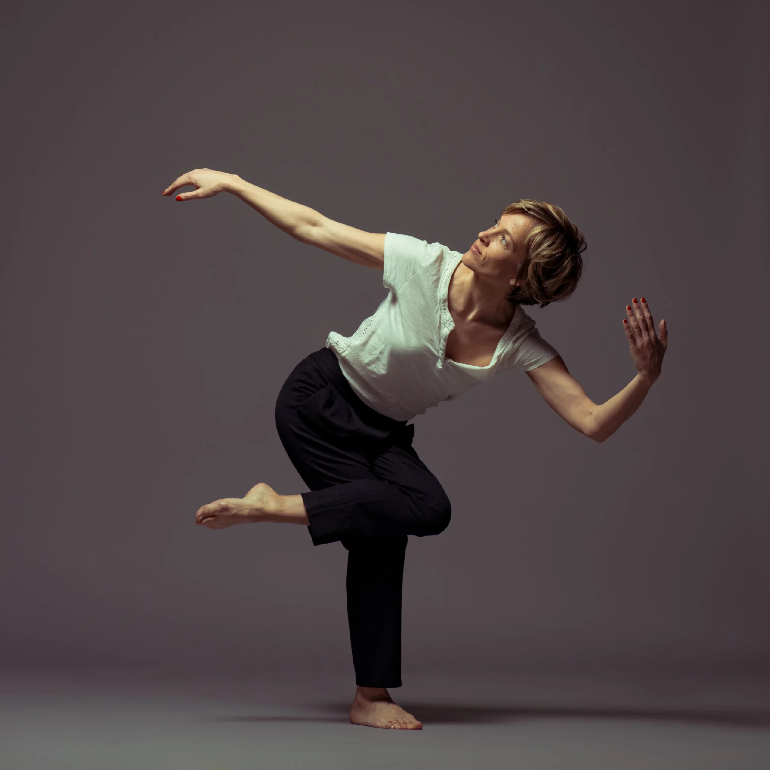 Marina, ancienne danseuse professionnelle, en pleine expression de mouvement fluide. Cette posture technique et gracieuse illustre son expertise du corps et du mouvement, fondement de la méthode Mov'Art®.